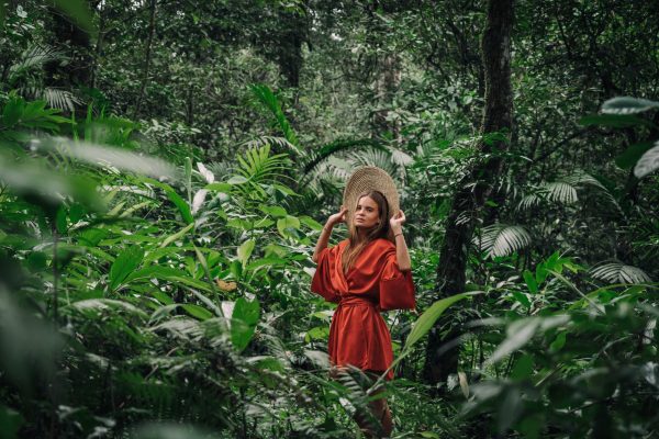 woman in a red silk dress posing in the middle of a forest